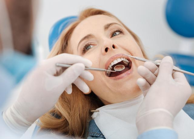 a woman is having her teeth examined by a dentist .