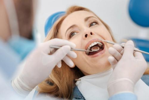 a woman is having her teeth examined by a dentist .