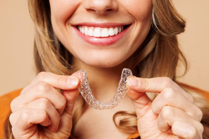 a woman is smiling while holding a clear brace in her hands .