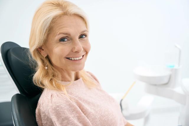 a woman is smiling while sitting in a dental chair .