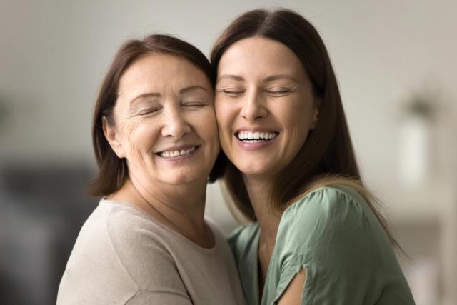 two women are hugging each other and smiling with their eyes closed .