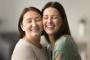two women are hugging each other and smiling with their eyes closed .