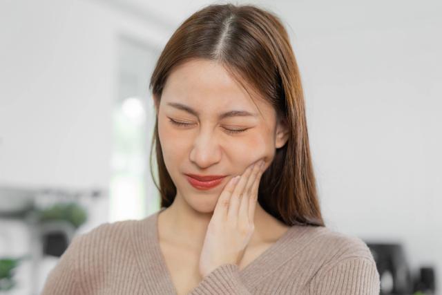 a woman is holding her face in pain because of a toothache .