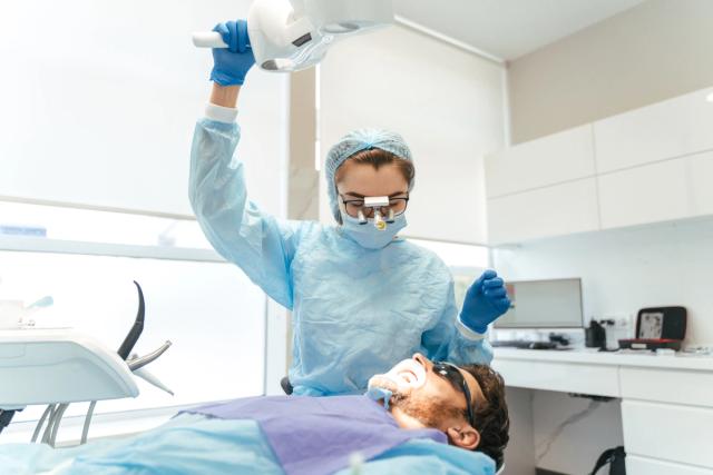 a dentist is examining a patient 's teeth in a dental office .