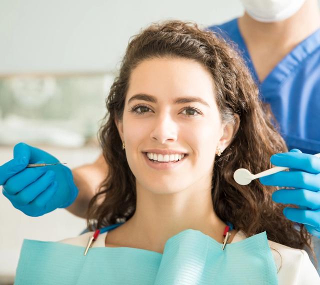 a woman is sitting in a dental chair while a dentist examines her teeth .