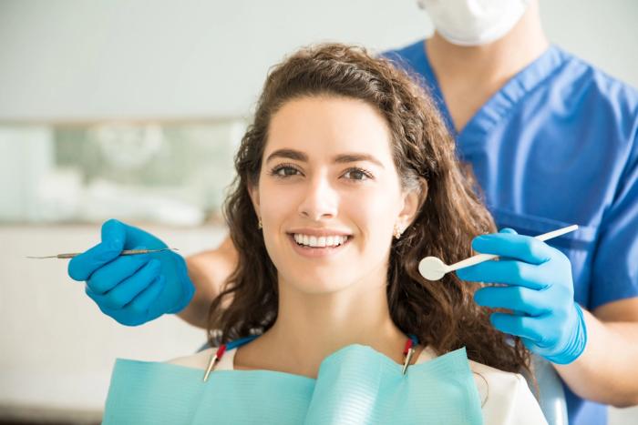 a woman is sitting in a dental chair while a dentist examines her teeth .