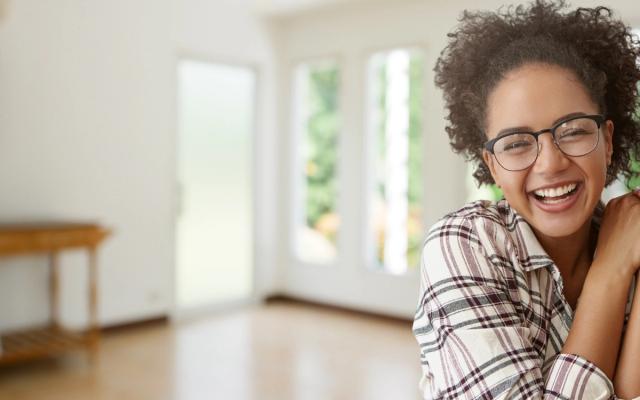 a woman wearing glasses is smiling in an empty room .