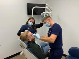 a man is sitting in a dental chair getting his teeth examined by two dentists .