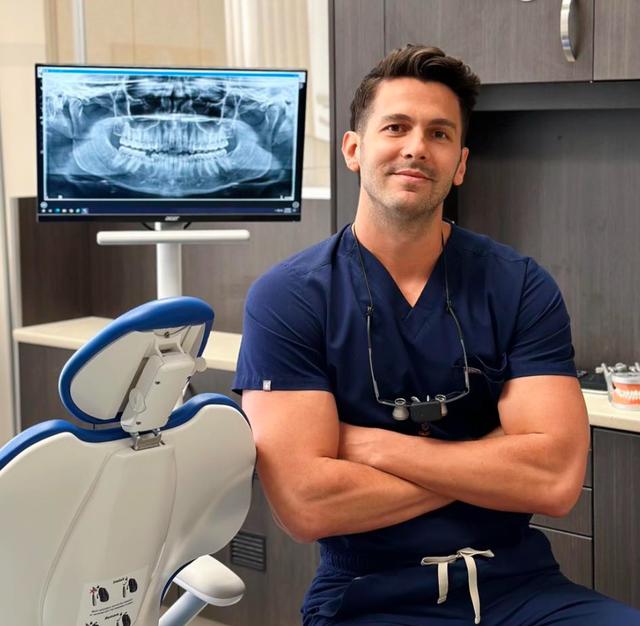a man is sitting in a dental chair with his arms crossed
