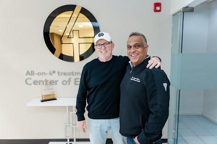 two men are standing next to each other in front of a sign .