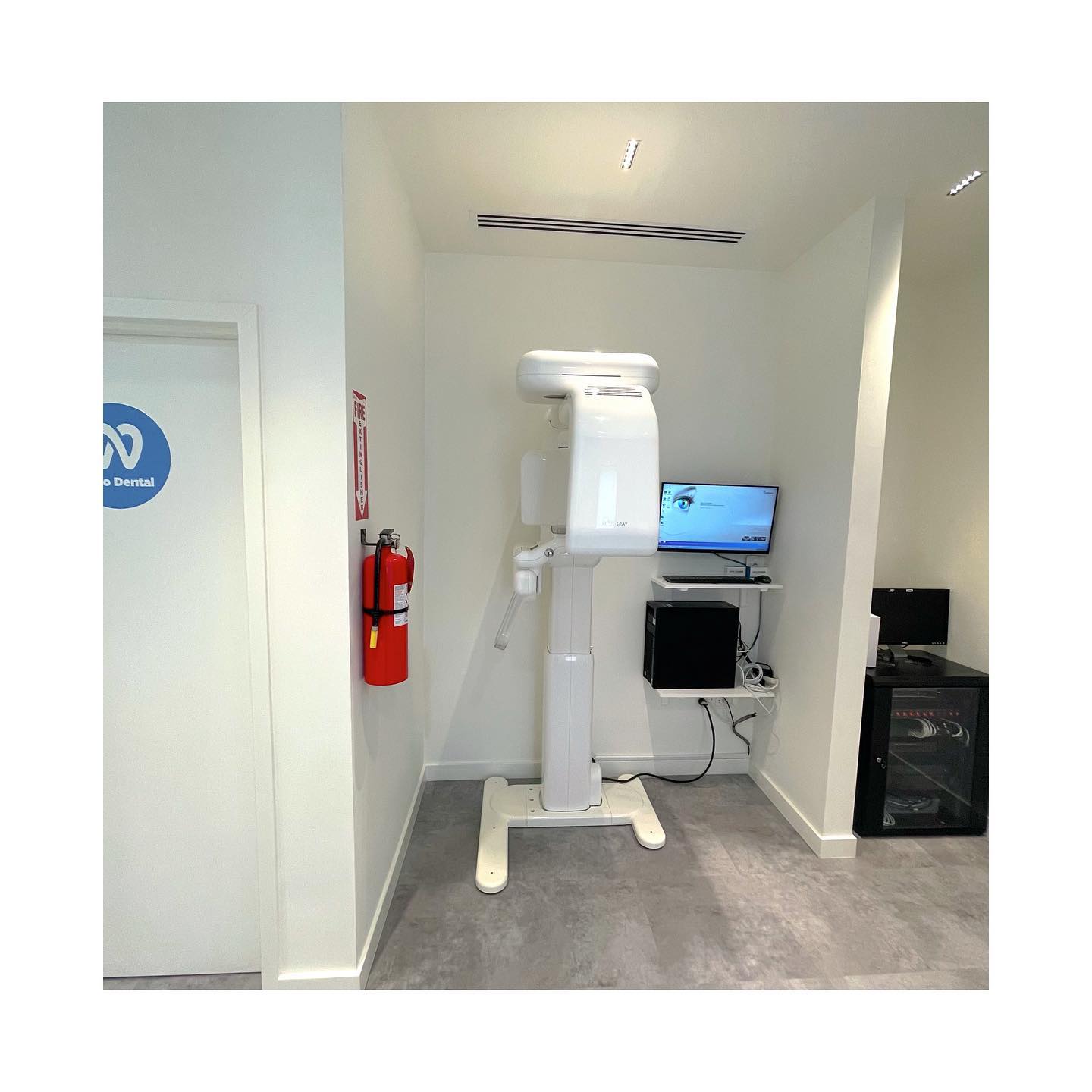 an x-ray machine is sitting in a room next to a fire extinguisher .