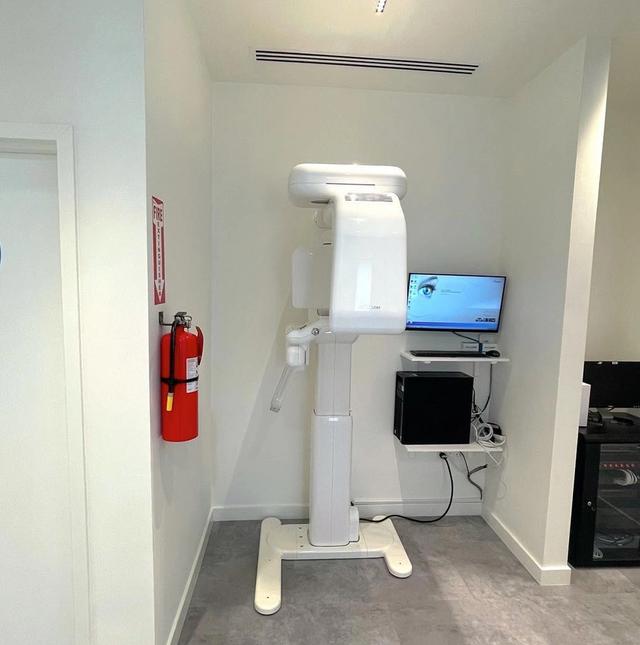 an x-ray machine is sitting in a room next to a fire extinguisher .