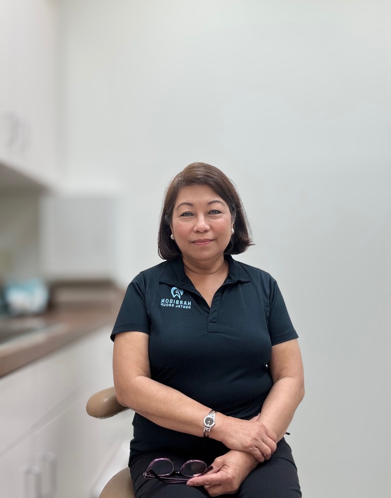 a woman in a black shirt is sitting in a dental chair .