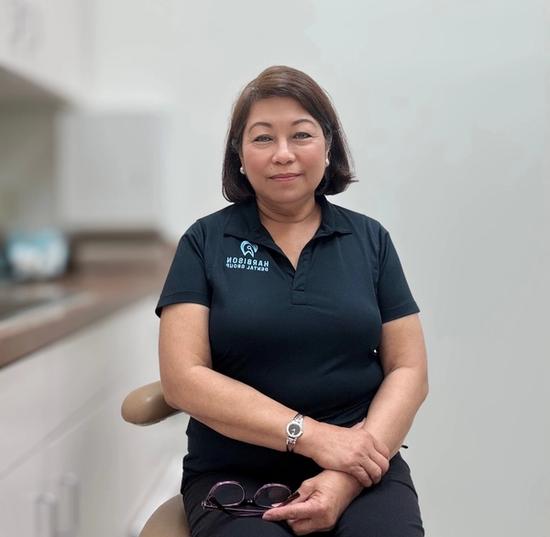 a woman in a black shirt is sitting in a dental chair .