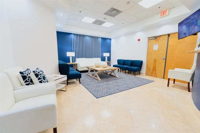 a waiting room with a couch , chairs , and a coffee table .