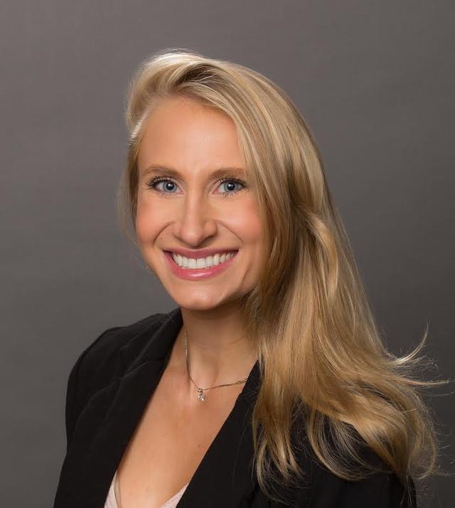 a woman wearing a black jacket and a pink shirt is smiling for the camera .