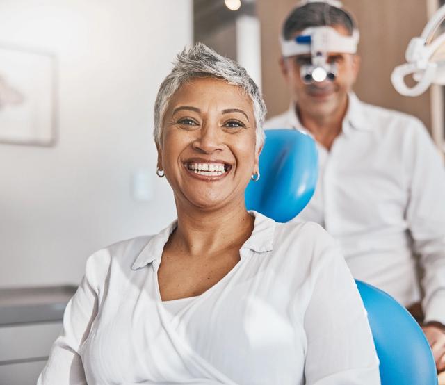 a woman is smiling while sitting in a dental chair .