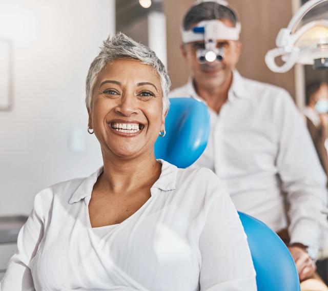 a woman is smiling while sitting in a dental chair .