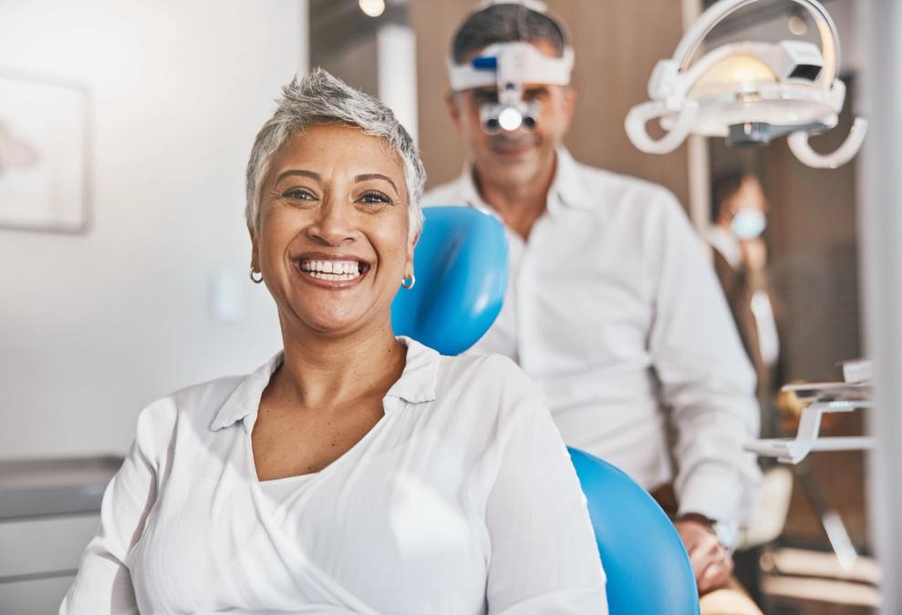 a woman is smiling while sitting in a dental chair .