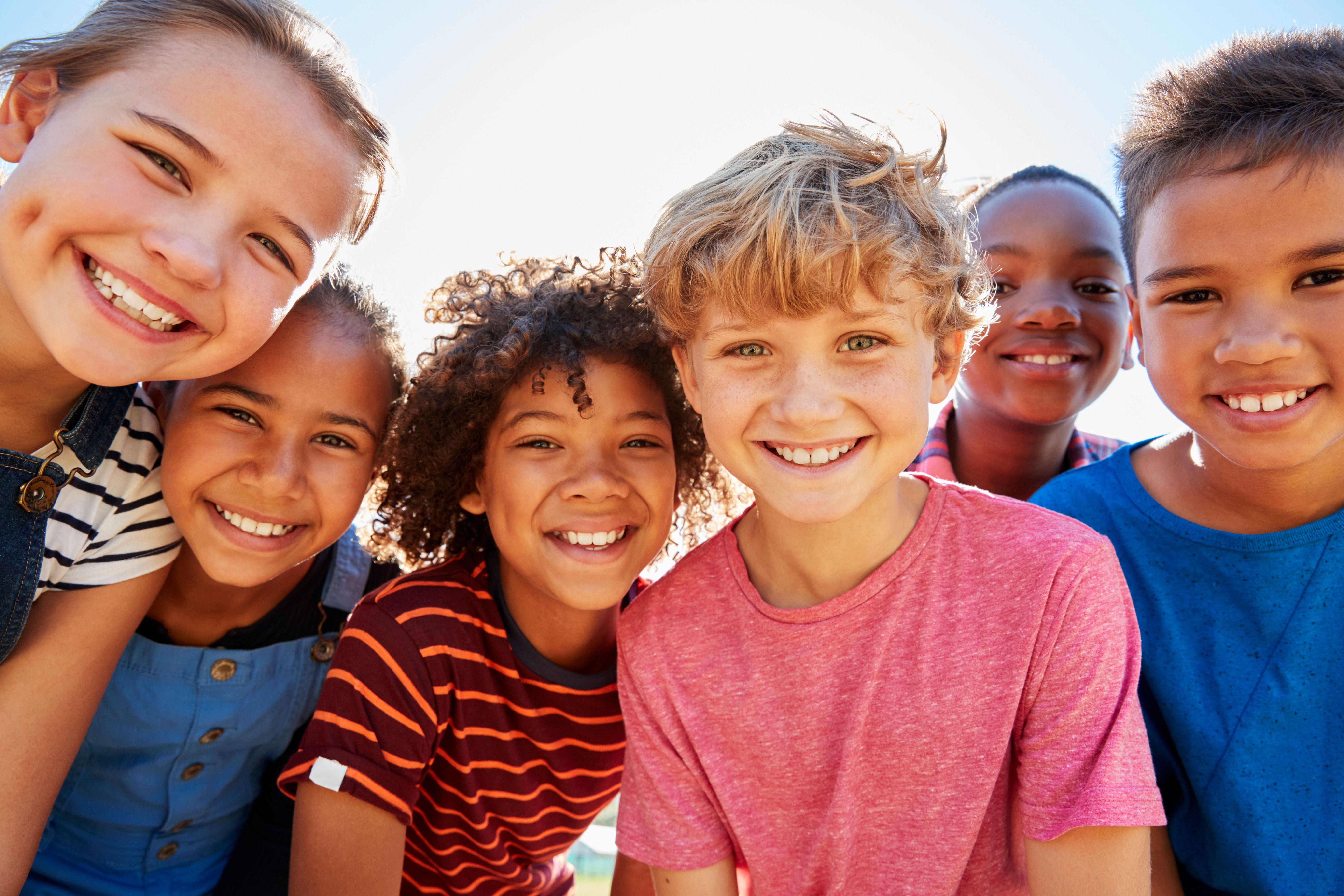a group of children are posing for a picture and smiling for the camera .