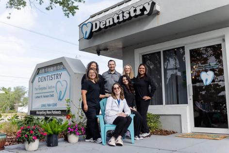 a group of dentists are posing for a picture in front of their dental office .