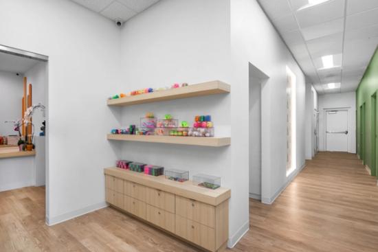 a hallway with wooden floors and shelves filled with toys .