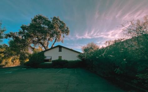 a house with a tree in front of it on a sunny day .