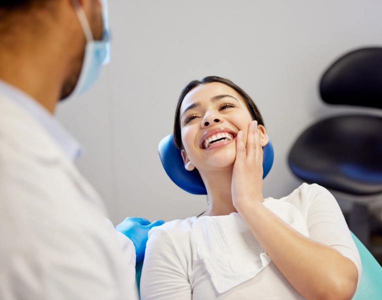 a woman is sitting in a dental chair smiling at the dentist .