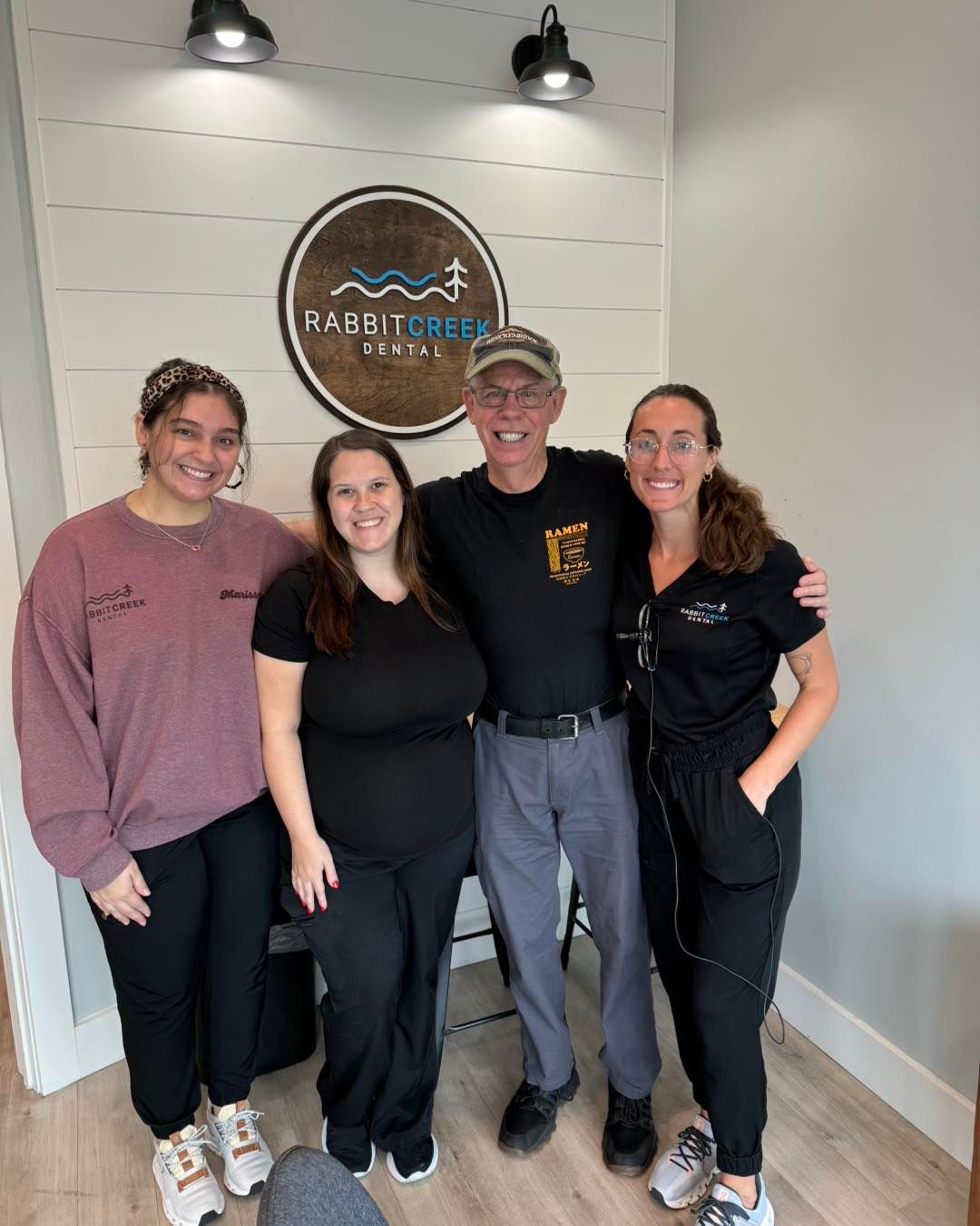 a group of people posing in front of a sign that says rabbit creek dental