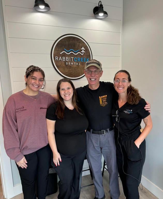 a group of people posing in front of a sign that says rabbit creek dental