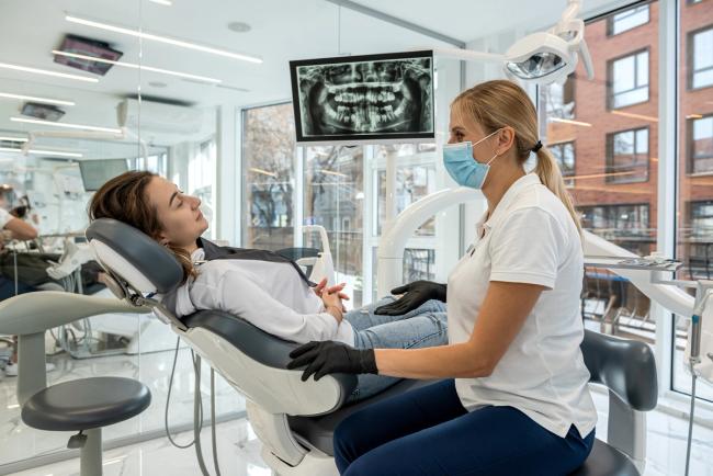 a female dentist is examining a patient 's teeth in a dental office .