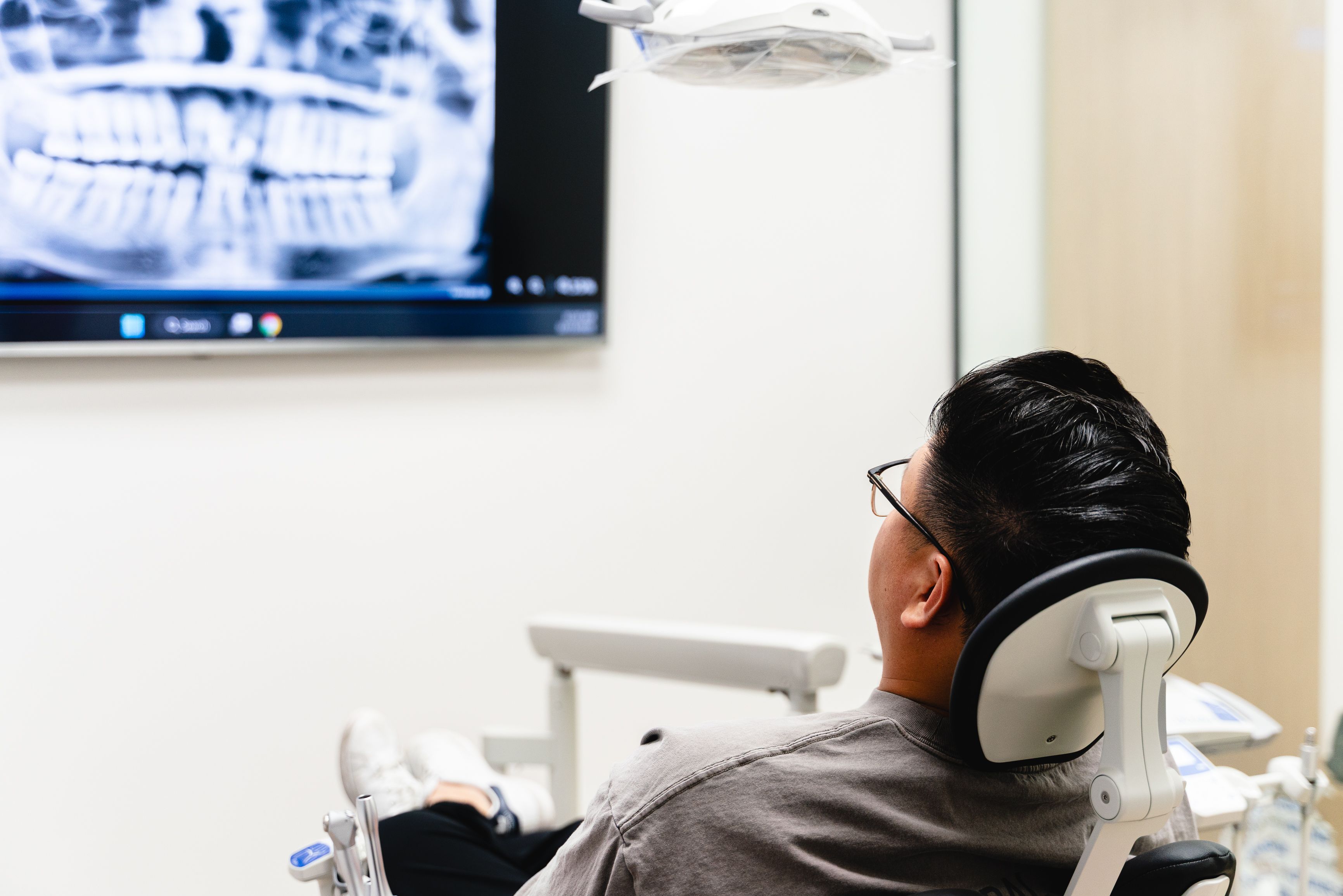 Patient in dental chair looking at a dental X-ray on a screen.