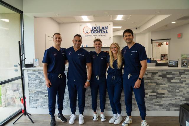 a group of dentists are posing for a picture in front of a dental office .