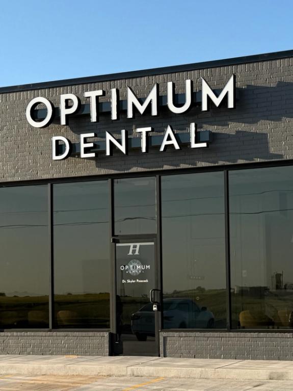 Exterior of Optimum Dental office with a gray brick facade and large windows.