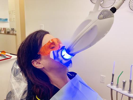 a woman is getting her teeth whitened in a dental office .