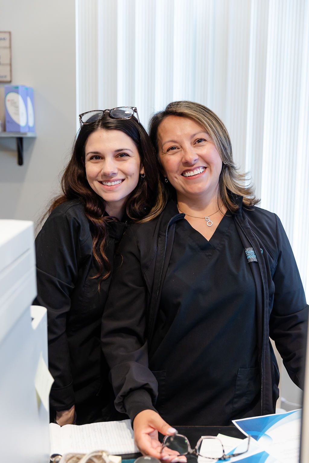 two women in black scrubs are posing for a picture .