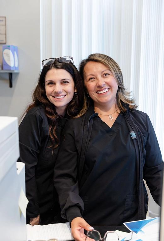two women in black scrubs are posing for a picture .