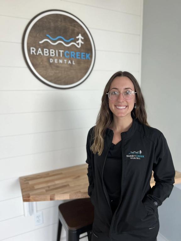 a woman is standing in front of a sign for rabbit creek dental