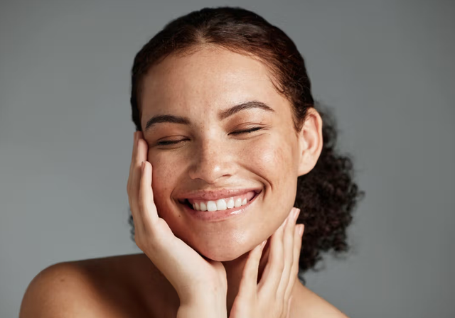 a woman is smiling and touching her face with her hand