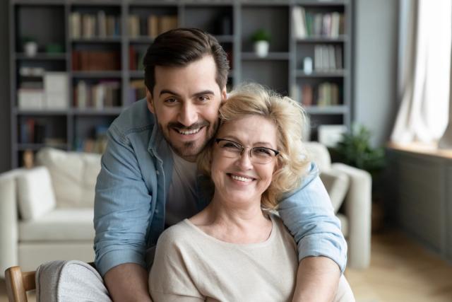 a young man is hugging an older woman in a living room .