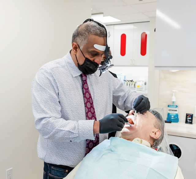a dentist examines a patient 's teeth in front of a bottle of listerine