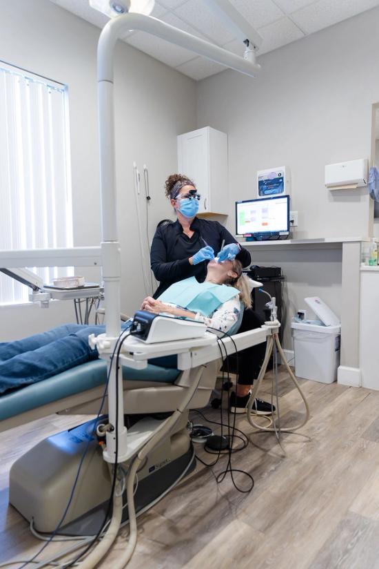 a woman is getting her teeth examined by a dentist