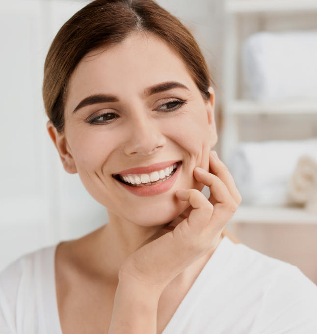 a woman is smiling and touching her face with her hand