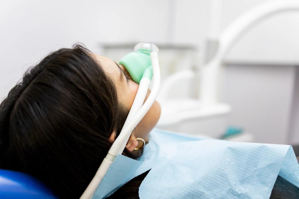 a woman is laying in a dental chair with an oxygen mask on her face .