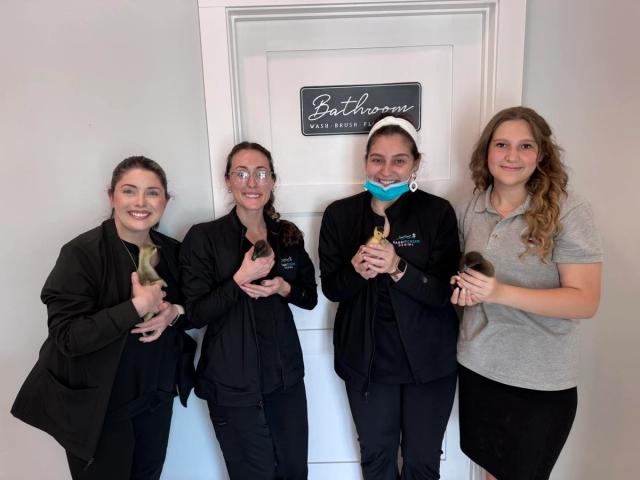 a group of women are posing for a picture in front of a bathroom door .