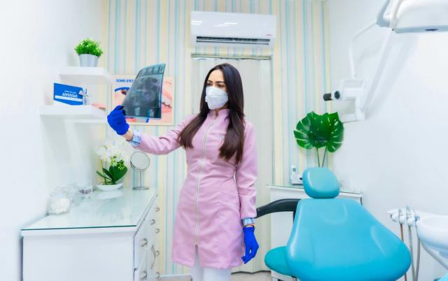 a female dentist is holding an x-ray in a dental office .