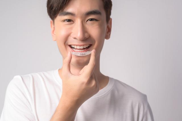 a young man is smiling while holding a clear brace on his teeth .