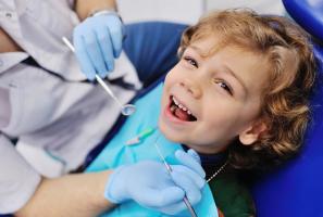 a young boy is sitting in a dental chair while a dentist examines his teeth .