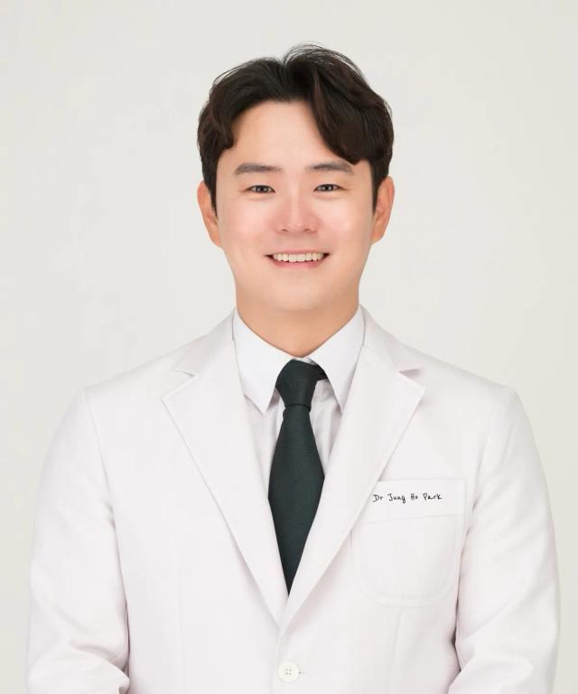 a man wearing a white jacket and black tie has the name dr. jung in park written on his chest