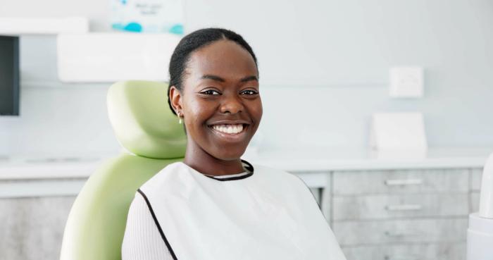 a woman is smiling while sitting in a dental chair .